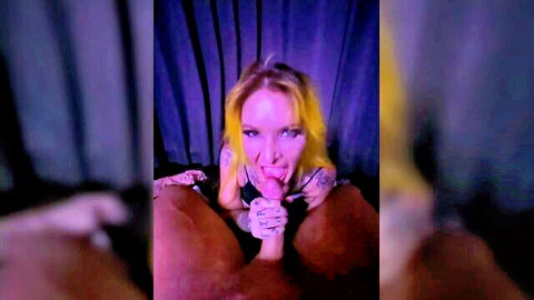 Blonde tattooed woman spreads shaved pussy lips wide with fingers while sticking tongue out seductively.
