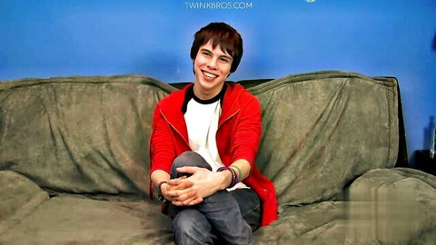 Kyler Moss smiling casually in red hoodie on couch