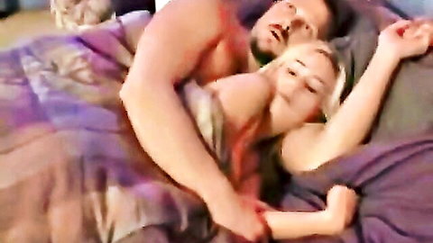 Muscular dad cuddling blonde daughter in bed, intimate post-sex moment
