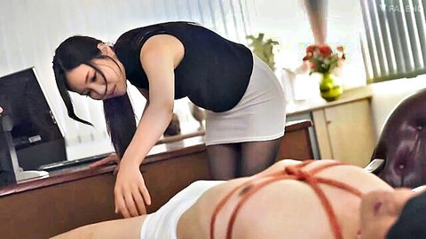 Asian office woman in mini skirt bending over bound man in BDSM scene