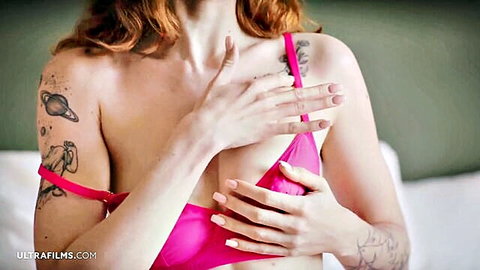Cherry Candle redhead in pink lingerie, hands covering breasts, tattoos