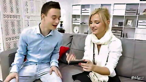 Blonde cutie shows phone to young man on couch