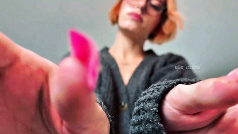 Elle Marz redhead in glasses and gray sweater, close-up pink nails POV