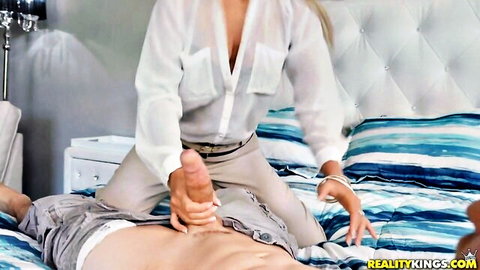 Blonde babe in sheer blouse strokes thick erect cock handjob on bed