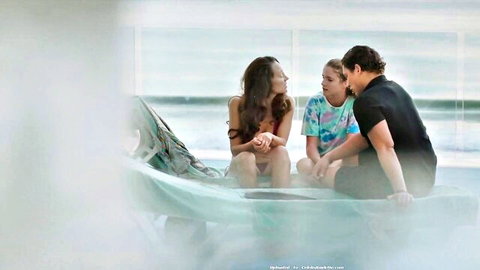 Brunette MILF in red bikini teases intimately with young girl and guy by pool
