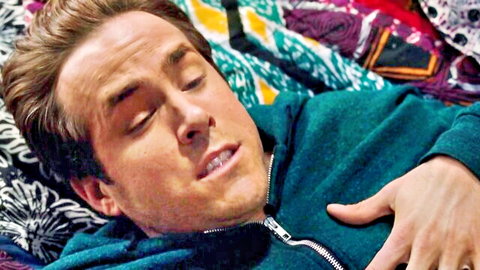 Handsome brunette man lying relaxed on colorful bed wearing green hoodie