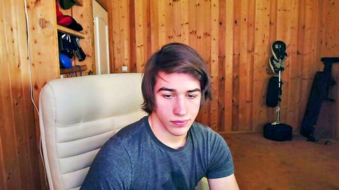 Shaggy-haired young twink gamer guy sits clothed in webcam stream solo tease