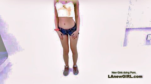 Cute slim teen with perfect body posing in crop top and short jeans for audition