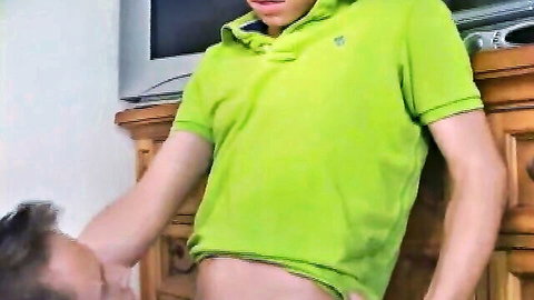Guy in green polo getting blowjob from kneeling brunette by wooden dresser