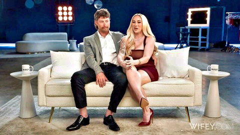 Busty blonde babe with huge tits in tight red dress plays Nintendo Switch with handsome tattooed guy on couch