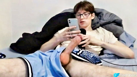 Nerdy twink stroking big dick while scrolling phone in bed