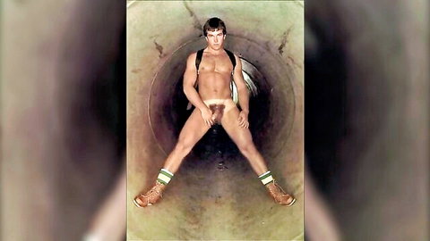 Vintage muscular hairy stud spreads legs wide showing huge cock bulge in tight jockstrap inside industrial pipe