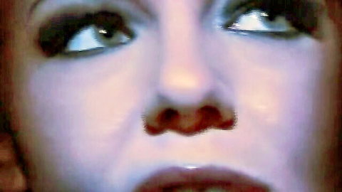 Close-up of redhead woman's wide smoky eyes and glossy open mouth in intense ecstasy