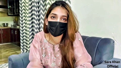 Stunning South Asian beauty Sara Khan in pink embroidered top and black mask teasing on couch
