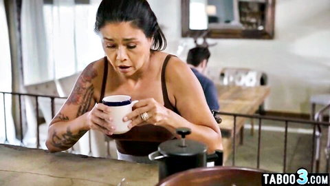 Tattooed Asian MILF in tank top holding coffee mug, cleavage view