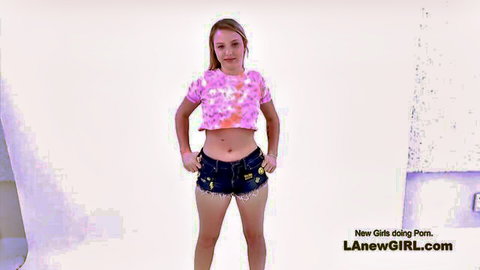 Petite freckled teen posing seductively in skimpy pink crop top and tiny denim shorts