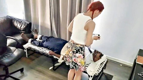 British redhead in white top and floral skirt over bound black man