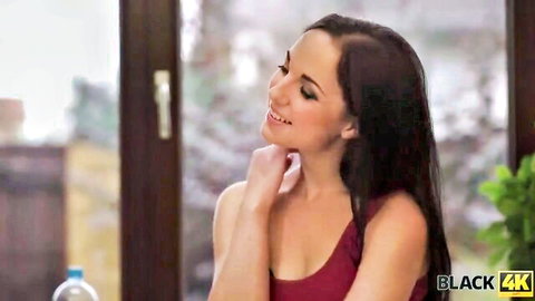 Seductive brunette smiling with hand on neck in tight red top showing cleavage