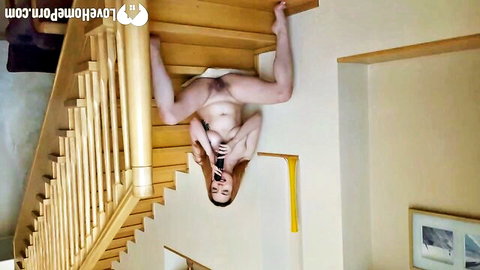 Upside-down naked young woman spreads shaved pussy on stairs holding phone selfie