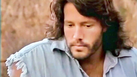 Handsome long-haired bearded man in torn denim shirt, intense seductive gaze