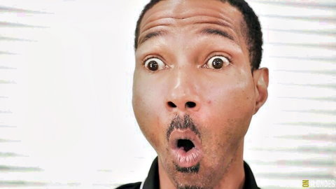 Shocked black man with wide eyes and open mouth in close-up reaction shot