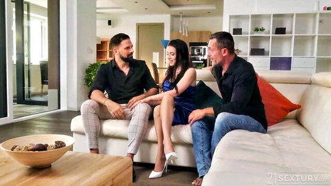 Nelly Kent in blue dress sitting with two men, teasing intense threesome