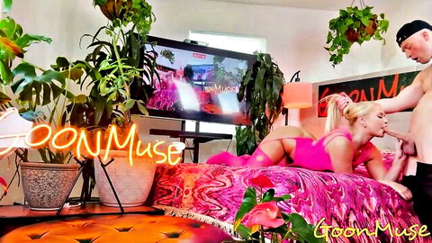 Skinny blonde in skimpy pink lingerie teased by shirtless guy's hand on bed in neon goonmuse room