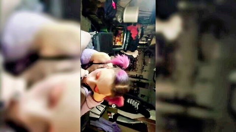Blurry close-up of pink-haired woman in car, eyes closed, wearing harness and boots