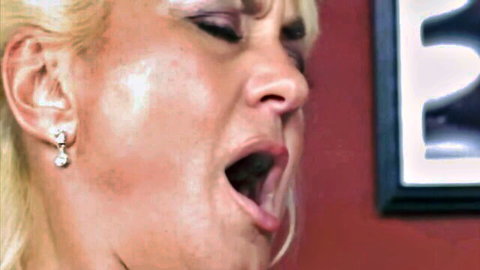 Blonde mature woman with wide open mouth and tongue out during intense blowjob closeup