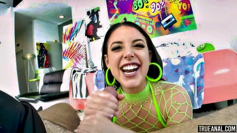 Smiling brunette in sheer green mesh lingerie grips huge pink dildo to her lips with hand gagging her face