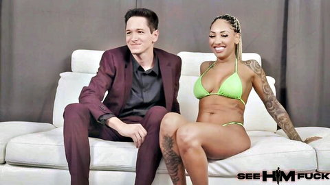 Kona Jade in green bikini poses with Toby Ryan on couch in See HIM Fuck scene
