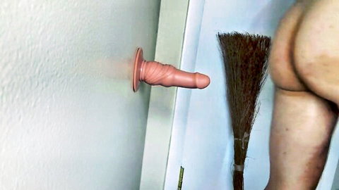 Pale bare ass standing and backing towards veiny pink dildo mounted on door with broom