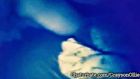 Blurry Chaturbate cam of Grayson Ollie in dim blue light, adult tease