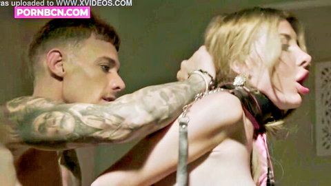 Tattooed stud chokes collared blonde babe by leash pulling head back exposing bare tits