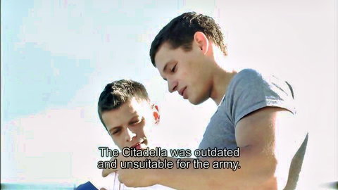 Two cute fit guys in gray shirts lean close in raw gay threesome preview