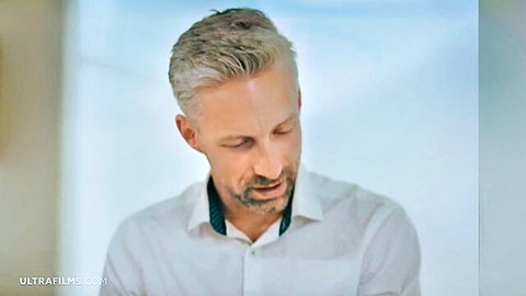 Handsome mature gray-haired man in white shirt looking down pensively