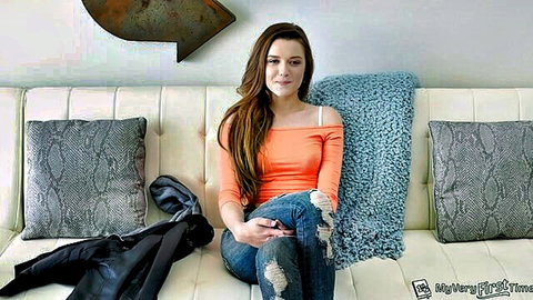 Alex Mae in off-shoulder orange top and ripped jeans, casual pose