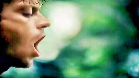 Intense close-up of curly-haired man yelling in jungle from Tarzan X adult parody