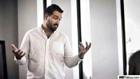 Bearded mature man in white shirt gestures openly in taboo office scene