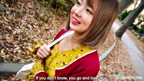 Smiling petite Japanese brunette in yellow floral top holding bag outdoors in forest