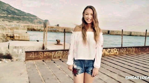 Taylor Sands smiling in white off-shoulder top and denim shorts at ocean pier