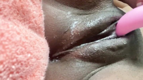 Ebony woman masturbating with pink dildo inserted close-up