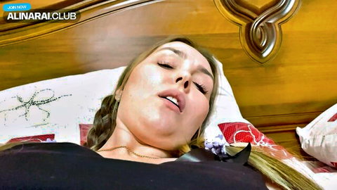 Alina Rai lying seductively in bed, aroused expression, blonde braid