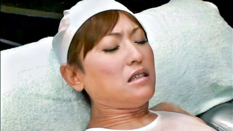 Asian nurse babe grimaces in ecstatic orgasm face with tongue out lying on bed in white uniform