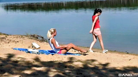 Blonde Ester and brunette Sara picnic by river in casual summer outfits
