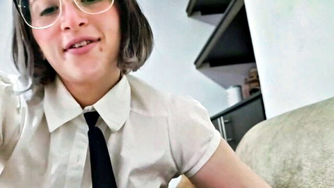 Glasses-wearing teen in white schoolgirl shirt and black tie smirks seductively with plump lips and cleavage tease