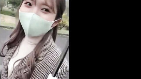 Cute masked East Asian woman smiling outdoors in checkered coat