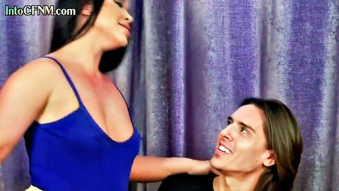Asian babe in tight blue top smiles down at kneeling guy in CFNM femdom tease