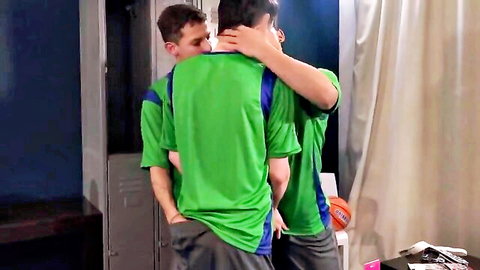 Two young athletic soccer players in jerseys, intimate embrace in locker room