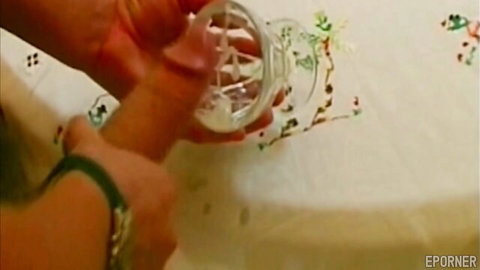 Feminine hands holding glass jar filled with thick white cum on floral tablecloth